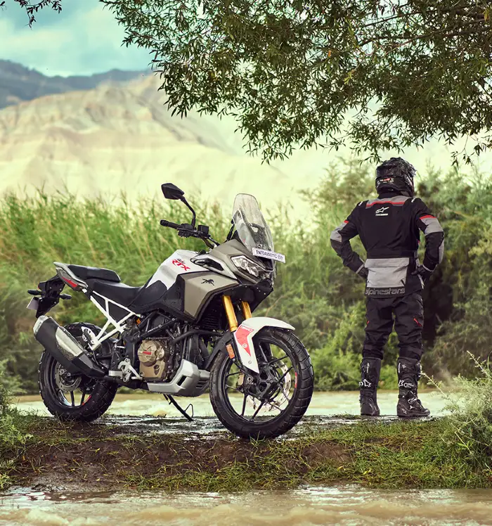 Foto de la Apache RTX 300 estacionada junto a motociclista descansando al lado de carretera