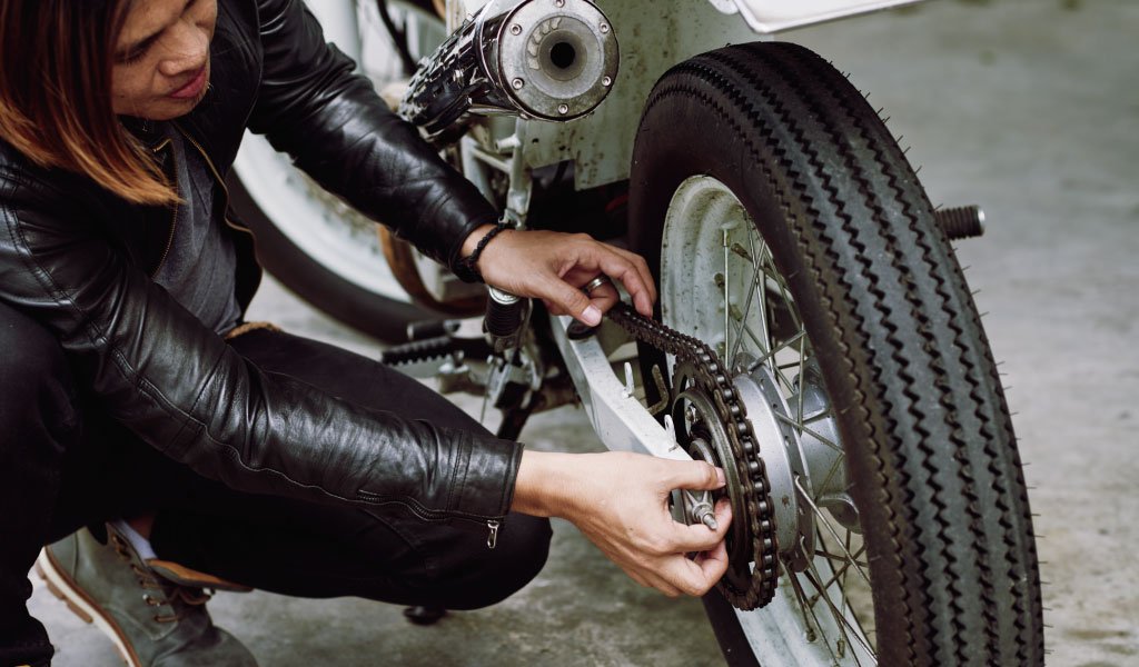 motorista arreglando su motocicleta o kit de arrastre antes de un paseo Cuándo reemplazar el kit de arrastre de tu moto: 7 señales que debes identificar 3 Foto de una motociclista arreglando su kit de arrastre